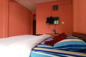 - une chambre avec un lit et une télévision murale dans l'établissement Pink Guest House, à Shillong