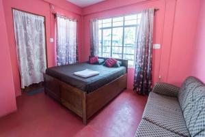 - une chambre avec un lit aux murs roses et une fenêtre dans l'établissement Pink Guest House, à Shillong
