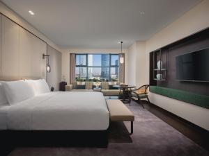 崑山市にあるHUALUXE Kunshan Huaqiao, an IHG Hotel - F1 Racing Preferred Hotelのベッド1台、薄型テレビが備わるホテルルームです。