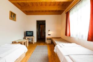 1 dormitorio con 2 camas, TV y ventana en Pensiunea Sapte Flori, en Gheorgheni