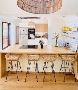 a kitchen with a counter with three bar stools at SunBliss Appartement in Saint-Gilles les Bains