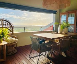 a room with a table and chairs and a large window at SunBliss Appartement in Saint-Gilles les Bains