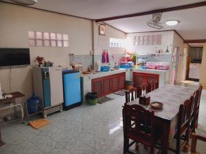 uma cozinha com uma mesa, um frigorífico, uma mesa e cadeiras em โฮมสเตย์ยายสฤษดิ์ (ซอย 17 ล่าง) em Chiang Khan