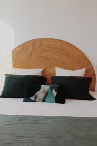a bed with black and white pillows and a wooden headboard at Le Rose Thé in La Ciotat