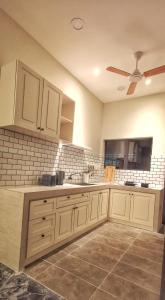 cocina con armarios blancos y ventilador de techo en IPOH AGONG HOMESTAY by ONE LIFE FOUR SEASON GUESTHOUSE en Ipoh