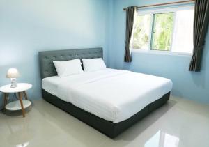 a bedroom with a white bed with a window at หมอกยามเช้า กะปง รีสอร์ท in Ban Mo