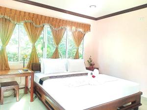 a bedroom with a bed and a desk and a window at Capital O 75415 Nanthachart Riverview Resort in Samut Songkhram
