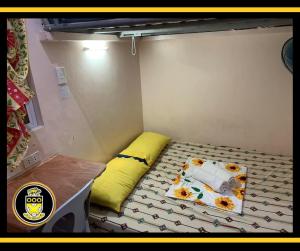 a small room with a bed with a yellow pillow at White Knights Dumaguete in Dumaguete