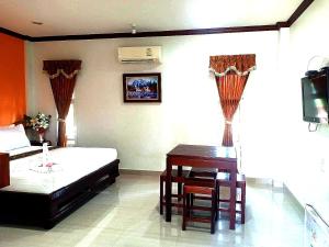 1 dormitorio con escritorio, 1 cama y 1 mesa en Capital O 75415 Nanthachart Riverview Resort, en Samut Songkhram