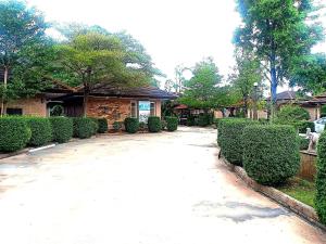 a driveway in front of a house with bushes at Capital O 75415 Nanthachart Riverview Resort in Samut Songkhram