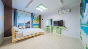 a bedroom with a bed and a tv and a window at Geojerowa Pension in Geoje 