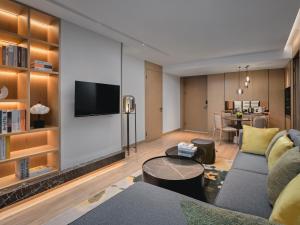 ein Wohnzimmer mit einem Sofa und einem TV in der Unterkunft Holiday Inn & Suites Kunshan Huaqiao, an IHG Hotel - F1 Racing Preferred Hotel in Kunshan