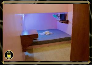 Cette petite chambre comprend un lit et une télévision. dans l'établissement White Knights Dumaguete, à Dumaguete