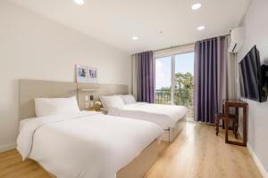 um quarto de hotel com duas camas e uma janela em Cordelia Hotel em Seogwipo