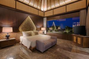 a bedroom with a bed and a television in it at Taman Dharmawangsa Suites in Nusa Dua