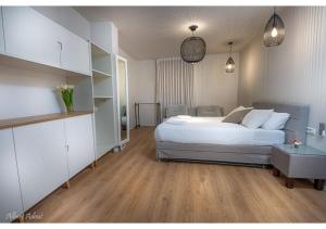 a bedroom with a white bed and a wooden floor at Dream House Tiberias in Tiberias