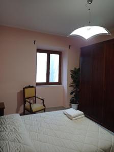 1 dormitorio con 1 cama, 1 silla y 1 ventana en Casa dei Faggi, en Tolfa