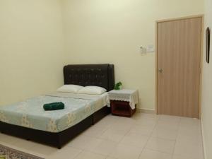a bedroom with a bed and a table and a door at Family Homestay Taman Vistana Indah Alor Setar in Langgar