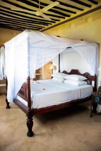 a bedroom with a canopy bed with white sheets and pillows at LAMU HOUSE in Lamu