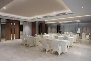 a banquet hall with white tables and white chairs at Hotel Santika Batam in Batam Center