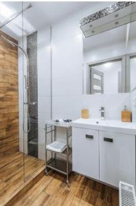 a white bathroom with a sink and a shower at White Apartment in Krakow