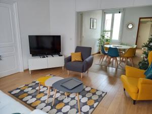 un soggiorno con TV, tavolo e sedie di La Petite Malouine a Dunkerque