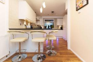 a kitchen with three bar stools in front of a counter at West Park House in Bramhope