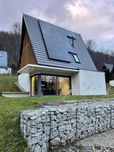 a house with solar panels on top of a stone wall at BosaRosa - domki nad zalewem in Wünschelburg