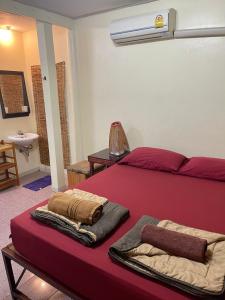 a red bed with two towels on it in a room at Hidden Lumpu in Bangkok