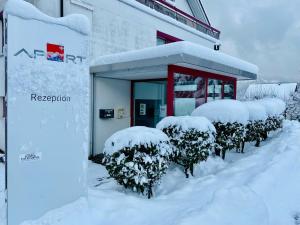 ein schneebedecktes Gebäude mit schneebedeckten Büschen in der Unterkunft Apart Holidays in Morschach