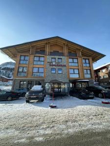 duży budynek z samochodami zaparkowanymi przed nim w obiekcie Hotel Gamsleiten w mieście Obertauern