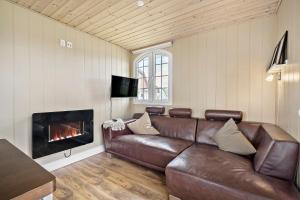 a living room with a leather couch and a fireplace at First Camp Hasmark Camping Resort & Cottages in Otterup