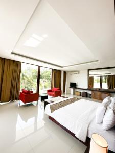 a bedroom with a large white bed and red chairs at The Wangsa Benoa in Nusa Dua