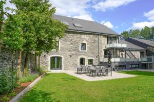 a stone house with a table and chairs in the yard at La Maison du Notaire in Houffalize