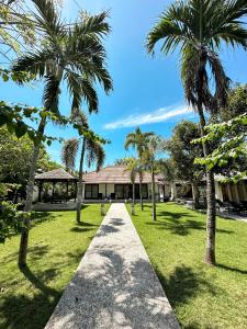 a walkway in front of a house with palm trees at The Wangsa Benoa in Nusa Dua