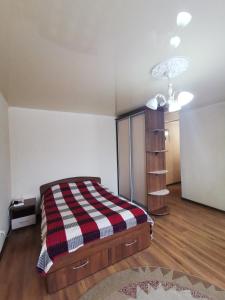 1 dormitorio con 1 cama con manta a cuadros en 1 комн апартаменты в центре рядом с парком, en Kostanái