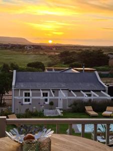 een wit huis met zonsondergang op de achtergrond bij Vinistrella in Kaapstad