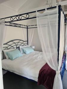 a bedroom with a canopy bed with blue pillows at Vinistrella in Cape Town
