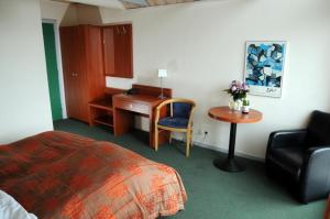 ヒアツハルスにあるHotel Hirtshalsのデスク、ベッド、椅子が備わるホテルルームです。