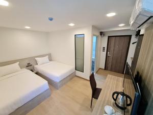 a hotel room with two beds and a television at Thana Wisut Hotel - SHA Plus in Bangkok