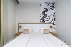 a bedroom with a large white bed with pillows at Hotel Sahat in Sarajevo