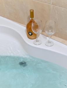 Atlantis luxury apartment first line to sea of galelli في طبرية: كأسين من النبيذ وزجاجة في حوض الاستحمام