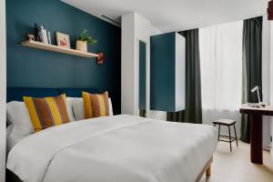um quarto com uma cama branca e uma parede azul em Edgar Suites Vicat - Porte de Versailles em Paris