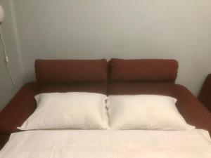 a bed with two white pillows and a brown headboard at REM One Bedroom Apartment in Thessaloniki