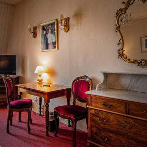 een kamer met een bureau, stoelen en een spiegel bij Hôtel Continental in Évian-les-Bains