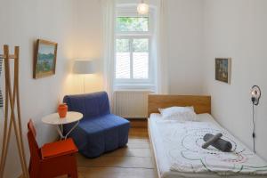 1 dormitorio pequeño con 1 cama y 1 silla azul en Schöna Einliegerwohnung, en Reinhardtsdorf