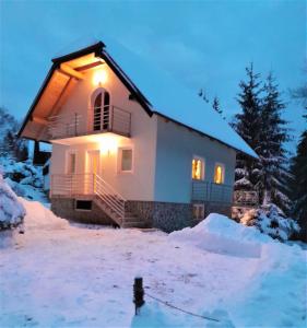 una casa en la nieve con luces encendidas en Holiday Home Kali, en Hočko Pohorje