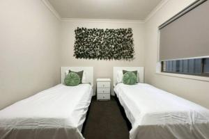 Comfort Heaven في كرايغيبورن: سريرين بيض في غرفة مع لوحة على الحائط