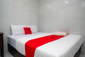 a bedroom with two beds with red and white sheets at RedDoorz near Danurejan Malioboro in Yogyakarta