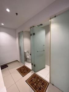 baño con aseo y puerta de cristal en Apartment with 2 Bedrooms, Trefoil @ Setia City (Imperia Asia Guest House), en Shah Alam